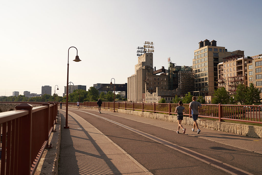 Couple running on stone arch bridge in minneapolis